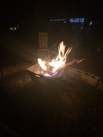 The fire pit blazing at night with camp chairs around it